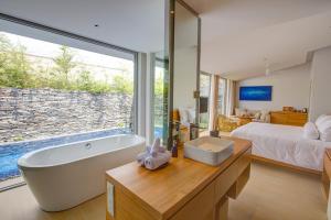 a bathroom with a tub and a bed and a large window at Naman Retreat in Da Nang