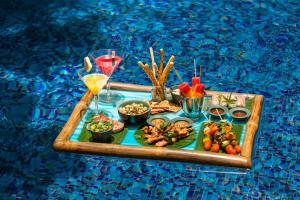 a tray with food and drinks on a table in a pool at Naman Retreat in Da Nang