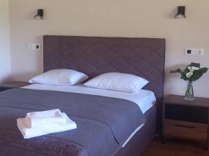 a bed with two pillows and a vase of flowers at Rustic village in Rijeka Crnojevića