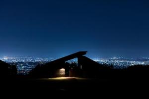 a building at night with a city in the background at Snow Peak YAKEI SUITE ABURAYAMA FUKUOKA in Fukuoka