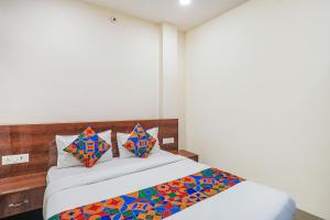 1 dormitorio con 1 cama con sábanas y almohadas coloridas en FabExpress Convivial Star en Raipur