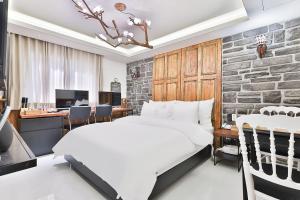 - une chambre avec un lit blanc et un mur en pierre dans l'établissement Riverside in February Gyeongbuk Gyeongsan Branch, à Gyeongsan