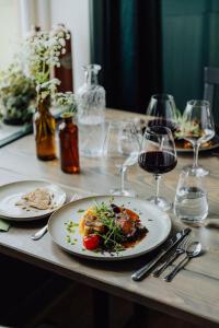 uma mesa com dois pratos de comida e copos de vinho em Trakt Forest Hotel em Holsbybrunn