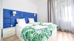 une chambre avec un lit avec une tête de lit bleue dans l'établissement Euronia, Sun & Snow, à Pobierowo