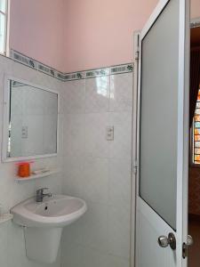 uma casa de banho branca com um lavatório e um chuveiro em KHÁCH SẠN HOÀNG TRÍ 89 (HOANG TRI 89 HOTEL) em Hố Nai