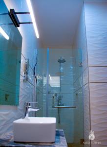 AVIEL SUITES AND HOTEL في Rubuchi: حمام مع حوض ودش زجاجي