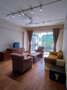 a living room with furniture and a large window at The Little Star Hotel & Studio at Star Regency Residence in Brinchang