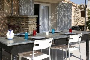 una mesa con sillas y platos en un patio en La maison du petit écolier, en LʼIsle-sur-la-Sorgue