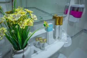 a vase filled with yellow flowers on a bathroom counter at AL KARNAK HOTEL - BRANCH in Dubai