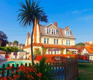 a house with a palm tree and a swimming pool at Yardley Manor Hotel in Torquay