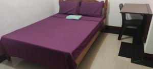 ein violettes Bett in einem Zimmer mit einem Tisch in der Unterkunft D & G Transient House in Pintuyan