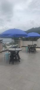 Trois tables de pique-nique avec des parapluies bleus sur un toit dans l'établissement D & G Transient House, à Pintuyan