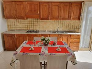 eine Küche mit einem Tisch mit roten Servietten und Blumen darauf in der Unterkunft Heron House Apartments in Agnone Bagni