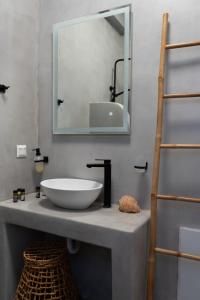 łazienka z umywalką i lustrem na ladzie w obiekcie Megusta Mykonos w mieście Tourlos