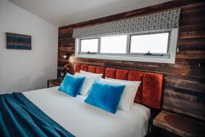 a bedroom with a bed with blue pillows and a window at Anchors Port Campbell in Port Campbell