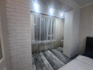 Zimmer mit einer weißen Ziegelwand und einem Spiegel in der Unterkunft Ашык Тобе in Almaty
