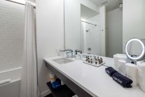 Baño blanco con lavabo y espejo en 121 Hotel by AvantStay Chic Modern Hotel In Nashville en Nashville