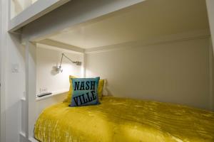 a yellow bed with a blue pillow on top of it at 121 Hotel by AvantStay Chic Modern Hotel In Nashville in Nashville