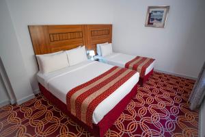 a hotel room with two beds and a red carpet at AL KARNAK HOTEL - BRANCH in Dubai