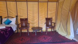una camera da letto con 2 sedie e un letto in una tenda di camp erg znaigui a Taouz