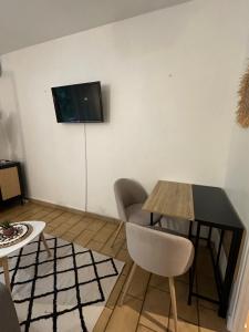 a living room with a table and a television on a wall at Charmant t1 dans le verdon in Gréoux-les-Bains