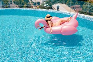 a woman riding on a pink raft in a swimming pool at Florida Nha Trang Hotel & Spa in Nha Trang