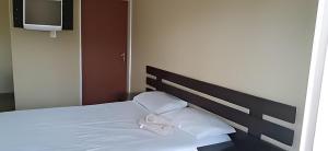 uma cama com duas almofadas brancas e uma televisão em Run n Fire em Mbabane