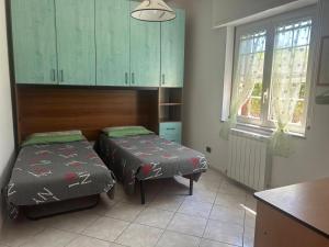 a room with two beds and a kitchen with green cabinets at Casa Sophie in Oristano