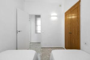 1 dormitorio con 2 camas y puerta de madera en Casa Las Calas, en Torrevieja