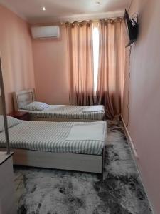2 camas en una habitación con ventana en NIYAT HOTEL, en Urganch
