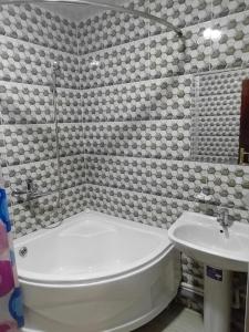 y baño con bañera blanca y lavamanos. en NIYAT HOTEL, en Urganch