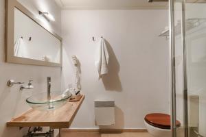 a bathroom with a glass bowl sink and a toilet at Hydra Hotel in Hydra