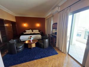 a hotel room with a bed and a table and chairs at Hotel Malta in Meknès