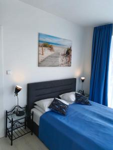 Schlafzimmer mit einem Bett mit blauer Bettwäsche und einem Fenster in der Unterkunft AZURE Baltic Apartamenty B&M in Kołobrzeg
