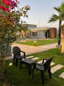 dos sillas y un banco en un patio con un edificio en شاليه S.W الفندقي, en Buraidah