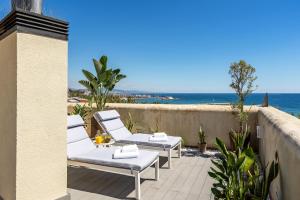 a patio with white lounge chairs and the ocean at Kronos on the Beach Attic Suite in Barcelona