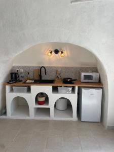 een keuken met een aanrecht met een wastafel en een magnetron bij Logement troglodyte tout confort 42 min tgv Paris in Naveil