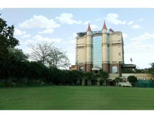 un gran edificio con un campo verde delante de él en Hotel Ans International, Raigarh,, en Raigarh