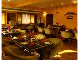 un restaurante con mesas y sillas y un hombre de pie en el fondo en Hotel Ans International, Raigarh,, en Raigarh