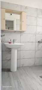 a white bathroom with a sink and a mirror at Ambla Apartaments Orikum in Orikum
