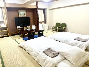 a hotel room with two beds and a flat screen tv at Hotel Tokeidai in Sapporo