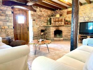 a living room with a stone fireplace and a tv at El currillo preciosa casa rural al lado cabarceno in Argomilla