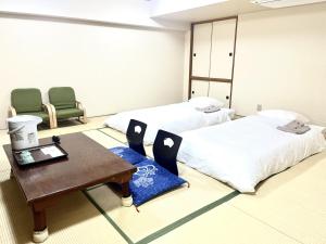 a room with two beds and a table and chairs at Hotel Tokeidai in Sapporo
