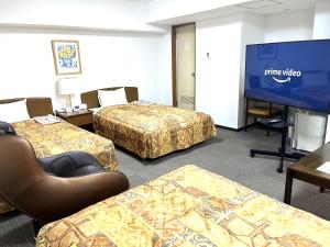 a room with three beds and a flat screen tv at Hotel Tokeidai in Sapporo