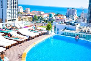 a pool on the roof of a building with people laying on chairs at Florida Hotel in Nha Trang