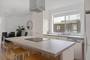 a white kitchen with a large island with stools at Prom Coast - Seabreeze in Sandy Point