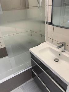 ein weißes Bad mit einer Dusche und einem Waschbecken in der Unterkunft Vittoria Immobilier-375-Vue mer- REGLEMENT SUR PLACE -Chèques Vacances acceptés in La Grande-Motte