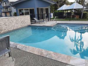a swimming pool with blue water in front of a house at Aloha Rainbow Beach in Rainbow Beach