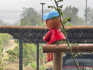 a teddy bear with a hat sitting on a fence at คูณ-เนื่อง ฟาร์ม สเตย์ หัวหิน Koon & Nueang Farm Stay Hua Hin in Ban Bo Fai (1)