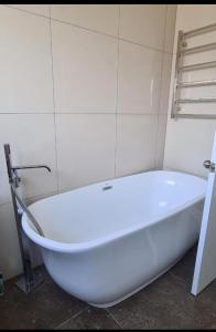 La salle de bains est pourvue d'une baignoire blanche. dans l'établissement Rare GEM in Westgate, à Auckland